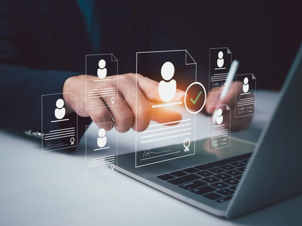Business professional using recruitment management software on a laptop to review and select candidate profiles digitally.